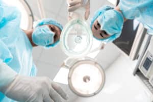Two serious doctors wearing blue masks and administering anesthesia for a surgery in Philadelphia.
