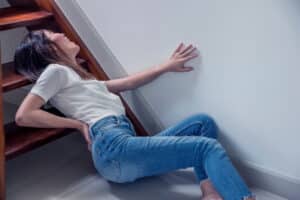 A woman lying on the ground after slipping and falling down the stairs