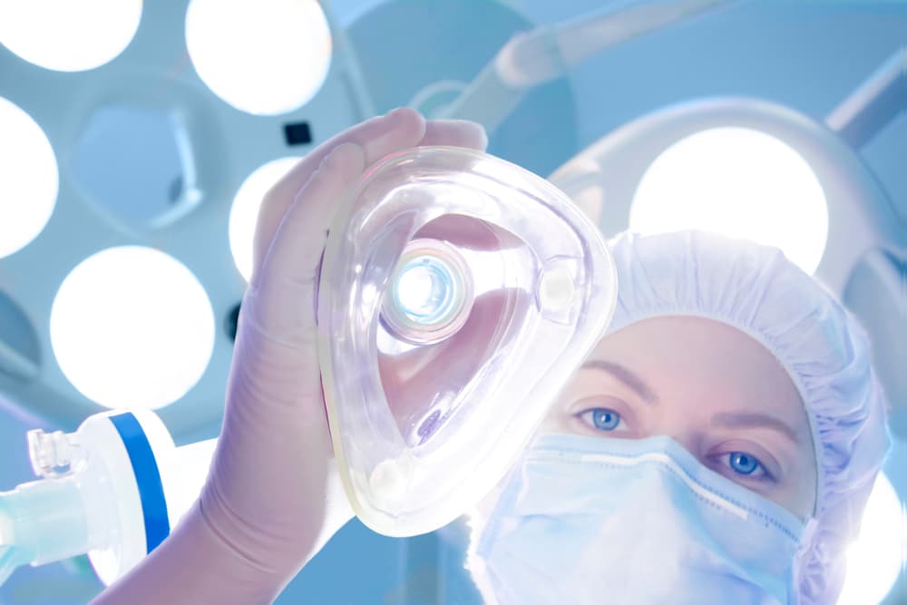 Anesthesiologist holds an oxygen mask to administer anesthesia to hospital patients.