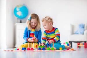 A young girl and boy playing with toys on the floor.