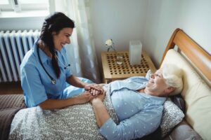 A nurse talking to a woman lying in bed in a nursing home