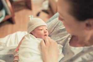 A woman holding a baby after a delayed cesarean section caused a birth injury