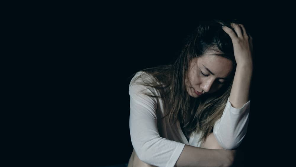 A female hazing injury victim sitting with her head in her hand