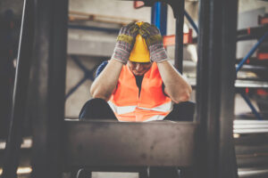A temporary worker holding his head in his hands after a workplace accident