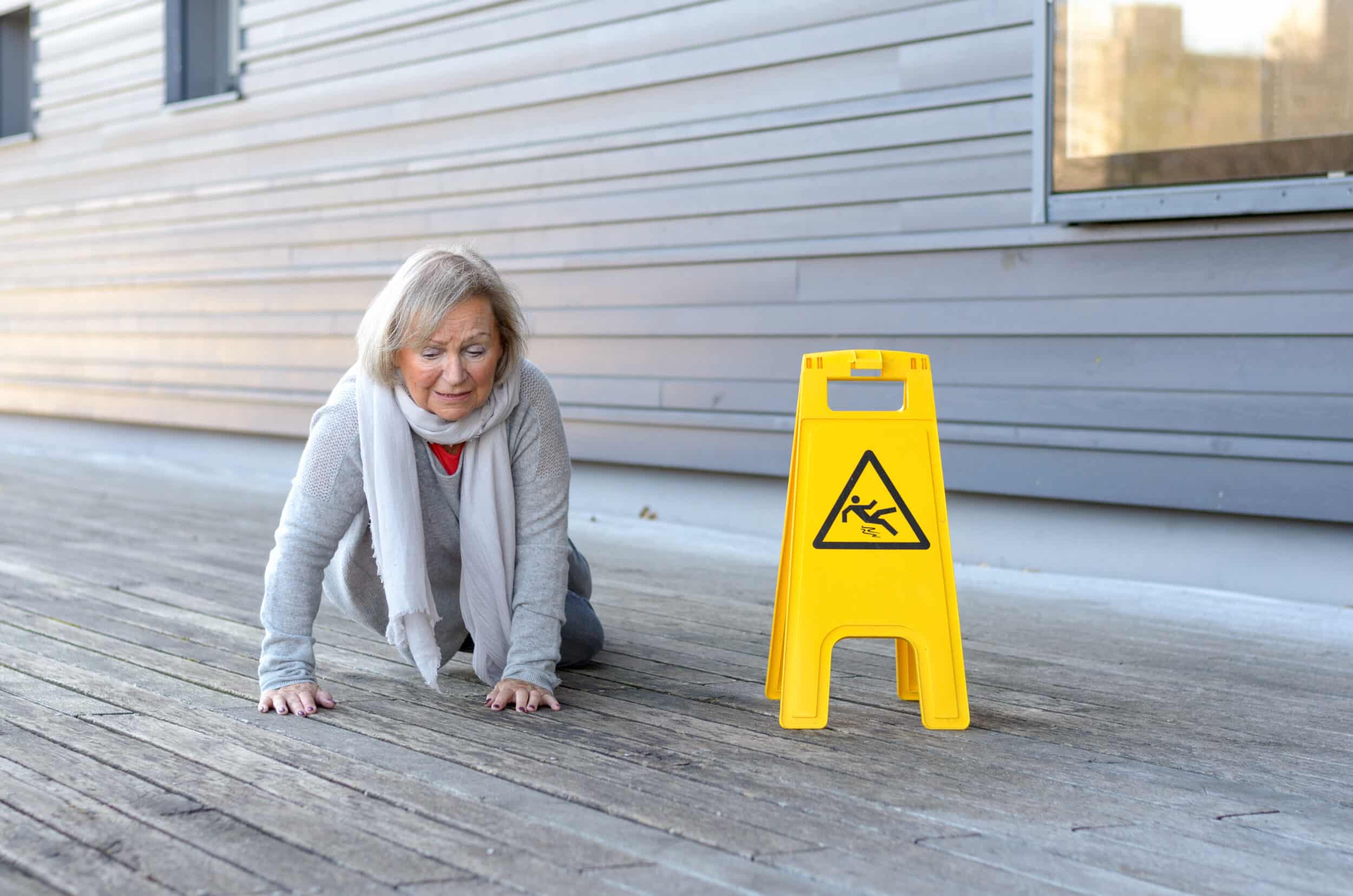 A senior woman on the ground next to a caution sign